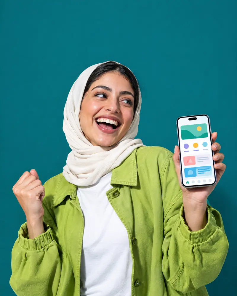A smiling woman raising her fist in delight while holding a phone with a clear app on screen