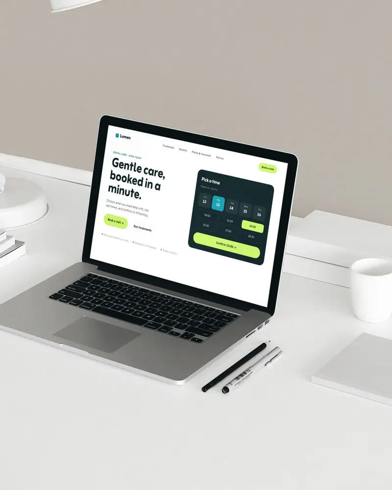 A laptop on a white desk showing a clinic website with a clear lime 'Book a visit' button and a time picker